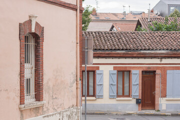 A view on a cozy tiny calm street in the old city during the day time with no people. Facade with light blue shutters. Brickwork around the arch windows. Roof tiles.