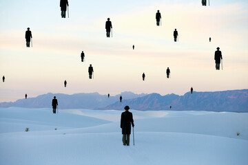 Men in bowler hats with umbrellas, outline of figures floating above ground, in a sand dune desert