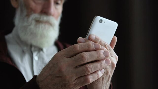 Elderly hands scrolling pictures in smartphone, online communication, internet