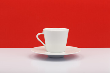 White ceramic coffee cup on white table with red background