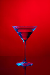 Martini glass on red background with blue light.