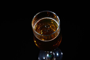 a glass of light beer on a black background.