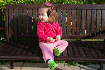 Menina sentada no banco tomando sol e olhando para seu lado direito
