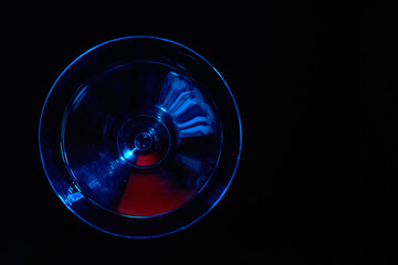 Martini glass with blue color on black background.