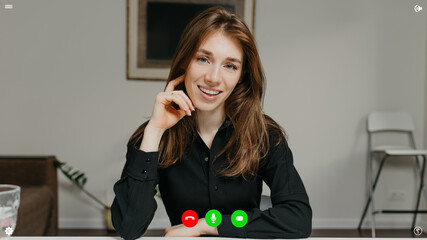A desktop computer screen view of the telecommunications application during a video chat on which the female team lead is listening a reportage about business at home.