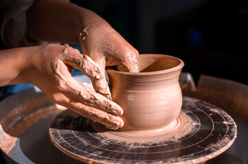 Potter master woman sculptor works with clay on a Potter's wheel and at the table with the tools. Close-up.