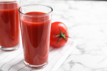 Delicious fresh tomato juice on white marble table, closeup. Space for text