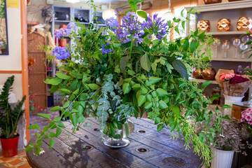 Fototapeta na wymiar flower arrangement with purple flowers, green leaves and eucalyptus on wooden table