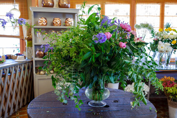 flower arrangement with purple and pinl flowers, green leaves and eucalyptus on wooden table