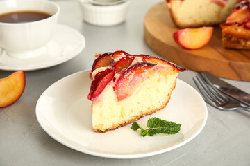 Slice of delicious cake with plums on light table, closeup
