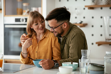 Young couple eating breakfast at home. Loving couple enjoying in the kitchen
