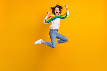 Fototapeta na wymiar Profile full size photo of hooray funny young woman jump wear rainbow sweater denim jeans white footwear isolated on yellow background