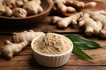 Dry ginger powder, fresh root and leaves on wooden table