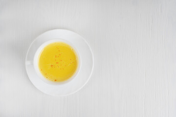 Top view of single cup of golden or turmeric milk which is Indian homemade popular drink used as alternative remedy to boost immunity served on plate on white wooden background. Image with copy space