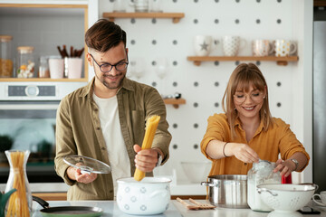 Husband and wife in kitchen. Young couple preparing delicious food at home.