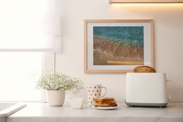 Modern toaster, flowers and tasty breakfast on counter in kitchen