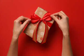 Woman with Christmas gift on red background, top view