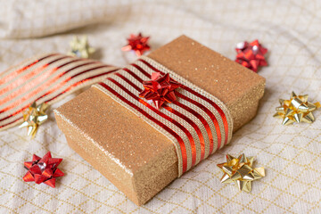 Shiny golden box with striped ribbon and colored bows. Concept Christmas gifts.