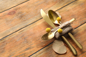 Set of cutlery and autumnal decor on wooden background, space for text. Table setting elements