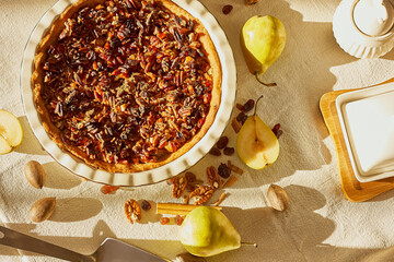 Home made pear tart with fresh pears and pecans on light linen tablecloth. Healthy eating sweet organic food concept. Selective focus. Top view.