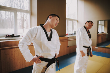 Two men stretch their necks while standing in gym.