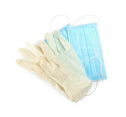 Medical gloves and protective face masks on white background, top view