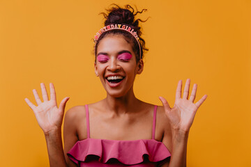 Funny african model with pink makeup expressing happiness. Charming birthday girl posing on yellow...