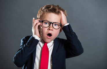 Obraz premium little boy in business suit with cell phone. child boss. fashionable kid in suit and tie and glasses. Back to business school.