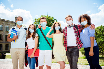 Photo portrait of young students hugging posing wearing face masks in campus park