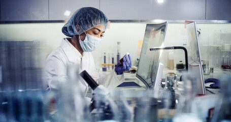 Asian female doctor working on biohazardous samples in laboratory. Using microscope