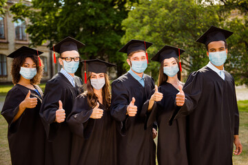 Photo portrait of six graduates showing ok-signs wearing face masks outdoors