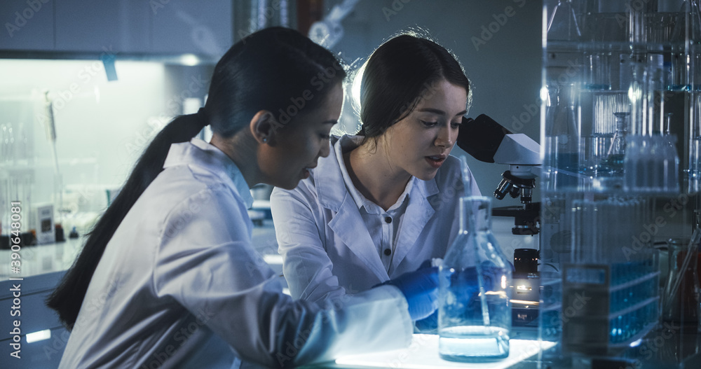 Wall mural multi ethnic female scientists working late in labolatory. using microscope