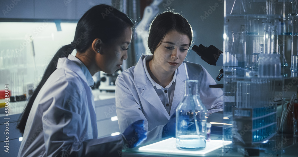 Wall mural multi ethnic female scientists working late in labolatory. using microscope