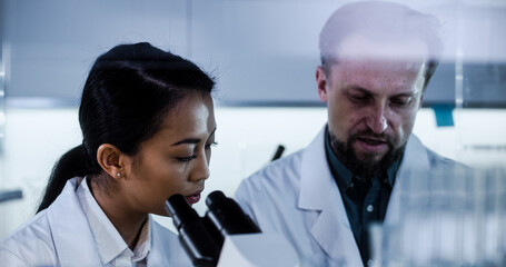 Multi ethnic team working in laboratory. Using microscope