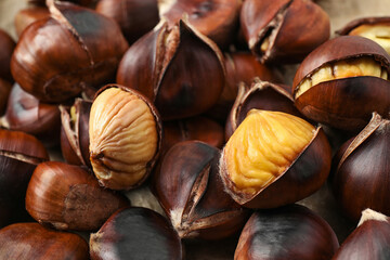 Pile of delicious edible roasted chestnuts as background, closeup