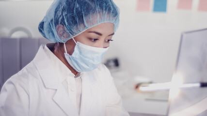 Modern laboratory. Asian female scientist working with microscope. Testing biohazardous samples