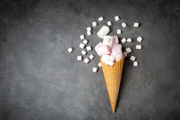 Waffle cone with marshmallows. Pink, white delicate marshmallow on a gray background. Favorite children's sweets.