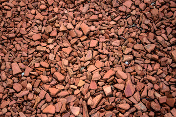 Red gravel on backyard road. Stones close up photo. Abstract background. 