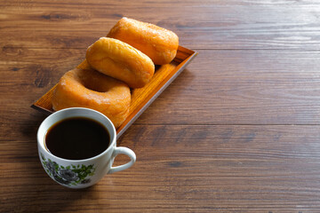 Fresh donut with cup of coffee on the wooden table