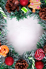 Christmas wreath with candy canes, mint candies, gingerbread cookies, cones and red baubles framing the copy space in the middle. Top view. New year background with sweets