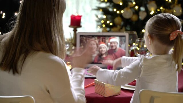 Two happy families with a children celebrating Christmas using a video call. Family greeting their relatives and friends on Christmas eve online. Social distancing, self isolation during quarantine