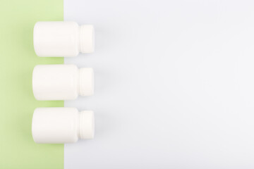 Flat lay with three unbranded jars with medication on light green and white background