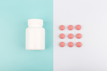 Flat lay with bottle and pills on blue and white background