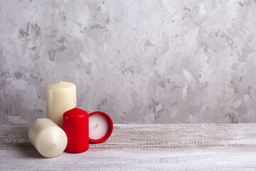 four candles on a wooden table, one red candle in a clay pot and a vanilla candle on the side, copy space for text.