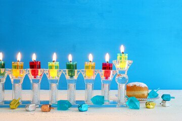 image of jewish holiday Hanukkah background with crystal menorah (traditional candelabra) and colorful oil candles