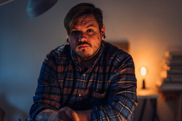 Chico joven alternativo con tatuajes delante de escritorio