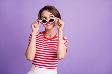Photo of young girl take off specs look up empty space wear sunglass striped t-shirt isolated violet color background
