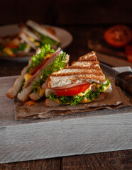 Sandwich with sauce, ham, vegetables and herbs on a dark wooden background