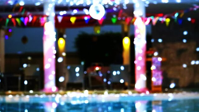 Reflection Blurred and bokeh dancing blue lights of party at luxury pool side