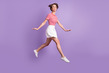 Full length profile photo of lady jump move send air kiss wear striped t-shirt short skirt sneakers isolated violet color background